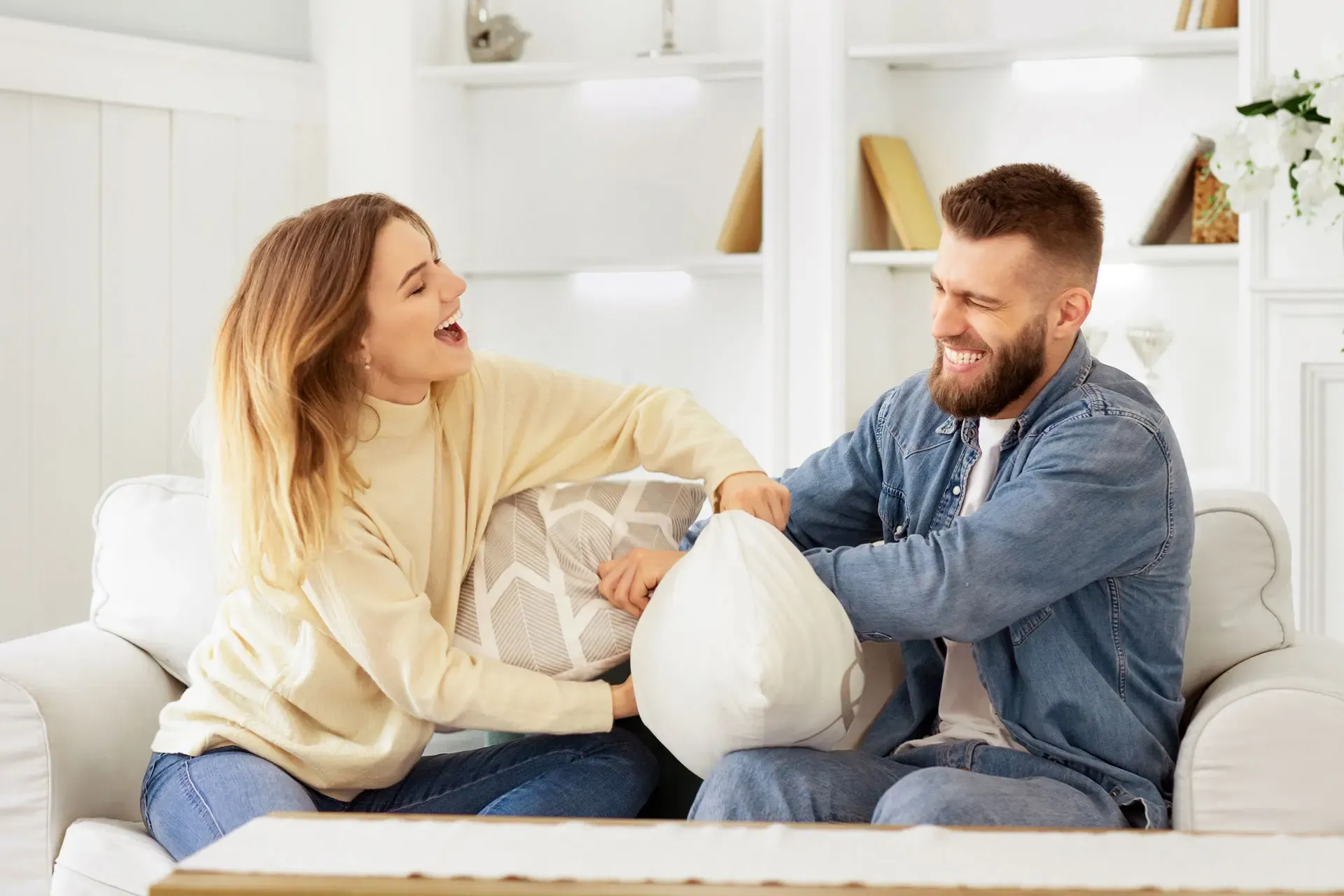 Lachendes Paar auf der Couch, das sich nach einer erfolgreichen Weisheitszahnentfernung entspannt