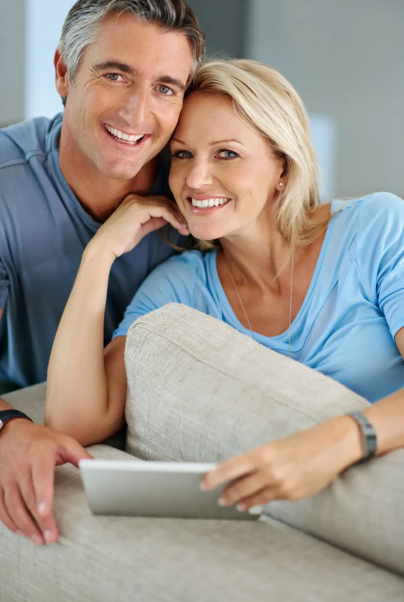 Glückliches Paar entspannt zu Hause nach einer erfolgreichen Wurzelbehandlung Revision und nutzt ein Tablet